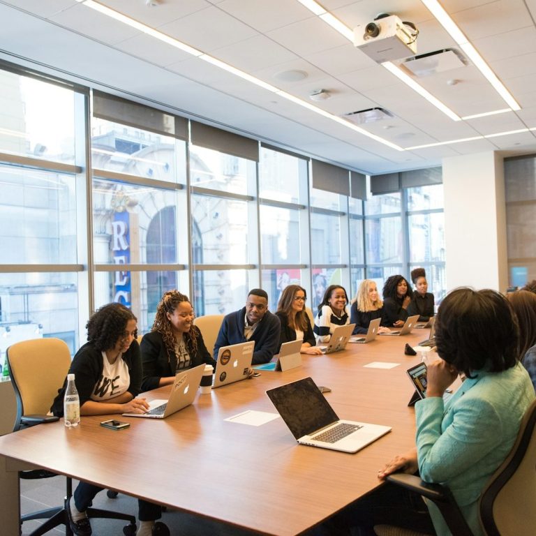 A group of people at a conference table, using laptops
